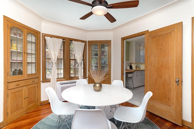 dining room featuring light wood-type flooring, a ceiling fan, and a wall mounted air conditioner