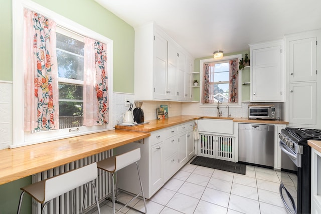 kitchen featuring appliances with stainless steel finishes, wooden counters, a sink, and open shelves