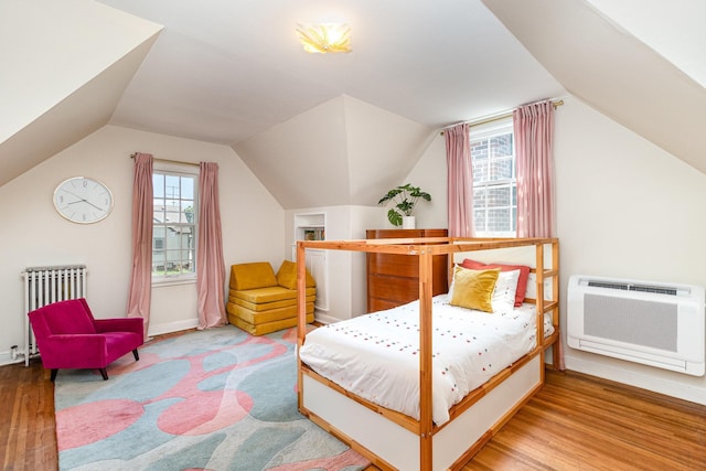 bedroom featuring radiator heating unit, wood finished floors, vaulted ceiling, heating unit, and baseboards