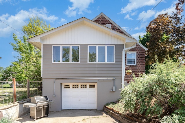 view of home's exterior featuring a garage, fence, driveway, and brick siding