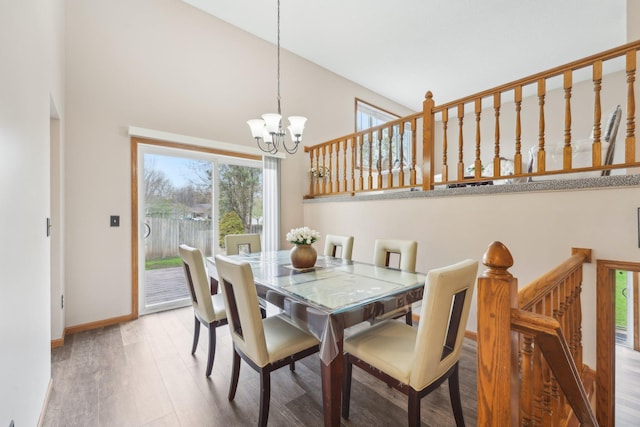 dining area with an inviting chandelier, baseboards, a high ceiling, and wood finished floors
