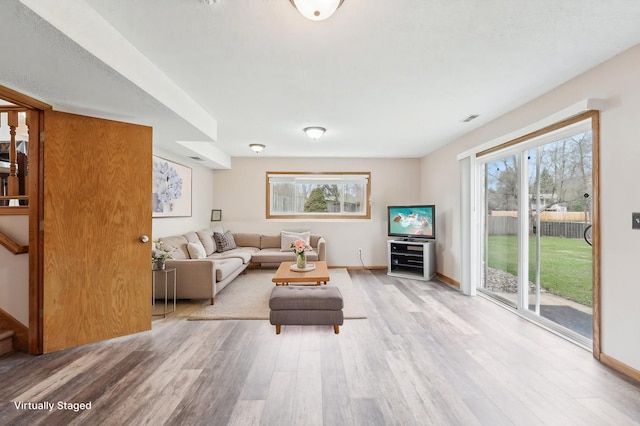 living area with stairway, baseboards, wood finished floors, and visible vents