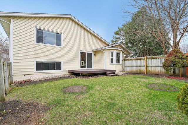 rear view of house with a fenced backyard, a wooden deck, and a lawn