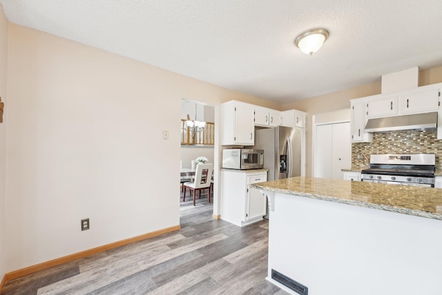 kitchen with under cabinet range hood, white cabinetry, appliances with stainless steel finishes, and wood finished floors