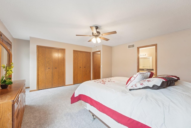 bedroom with multiple closets, light carpet, a ceiling fan, and visible vents