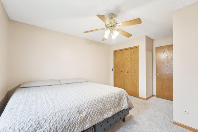 carpeted bedroom featuring a closet, baseboards, and a ceiling fan