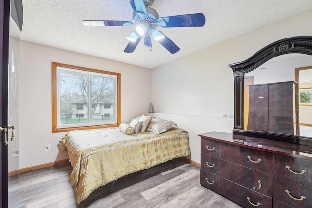 bedroom featuring baseboards, ceiling fan, a textured ceiling, and wood finished floors