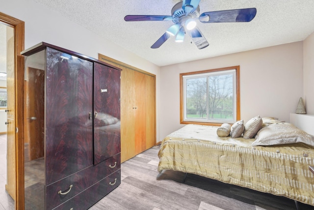 bedroom featuring a ceiling fan, a closet, a textured ceiling, and wood finished floors