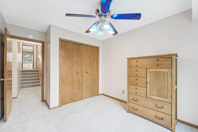 bedroom featuring baseboards, ceiling fan, a closet, and light colored carpet
