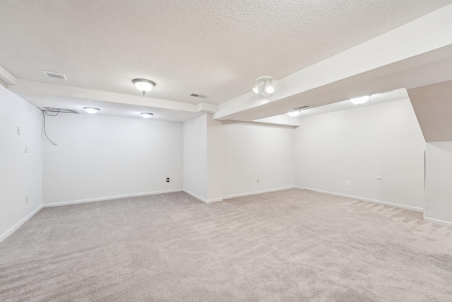 finished below grade area featuring baseboards, light colored carpet, and visible vents