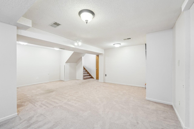 finished basement with visible vents, a textured ceiling, carpet floors, and stairway