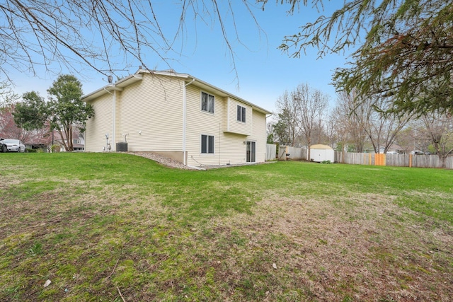 view of side of home featuring fence, a storage unit, and a lawn