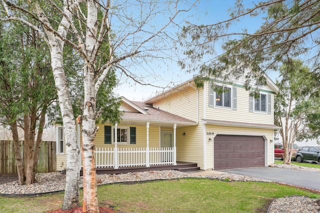 traditional-style house featuring covered porch, a front yard, a garage, fence, and aphalt driveway