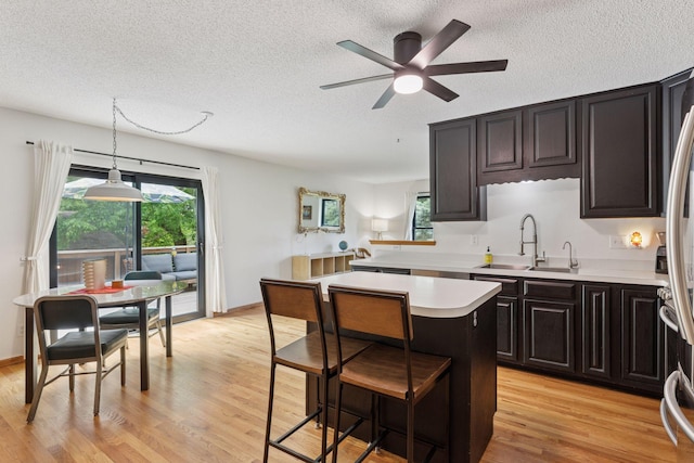 1283 Bidwell St, West Saint Paul, MN 55118 - kitchen featuring light countertops, a kitchen island, a textured ceiling, a sink, and light wood-style flooring