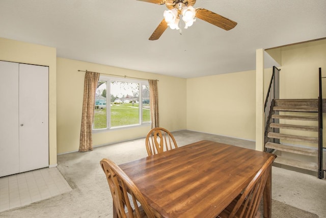 dining area with carpet flooring, ceiling fan, and stairway