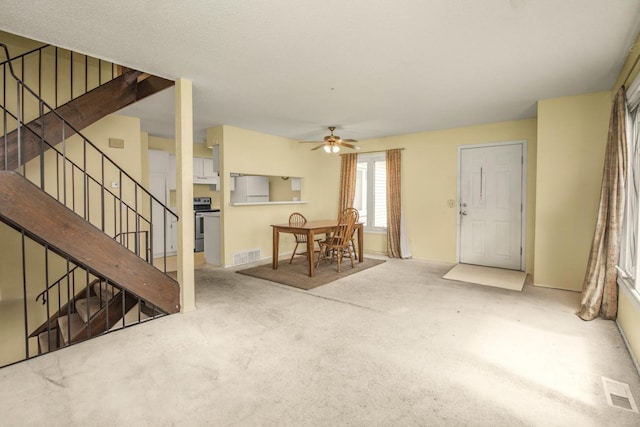 living room with a ceiling fan, visible vents, stairway, and carpet