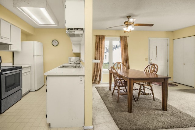 kitchen with white cabinetry, a sink, ceiling fan, light countertops, and electric range