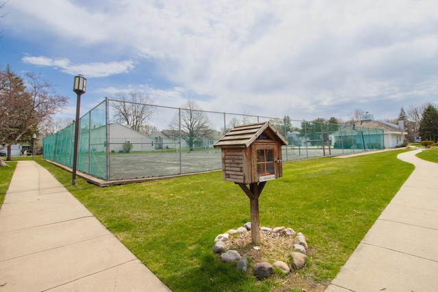 surrounding community featuring a tennis court, a lawn, and fence
