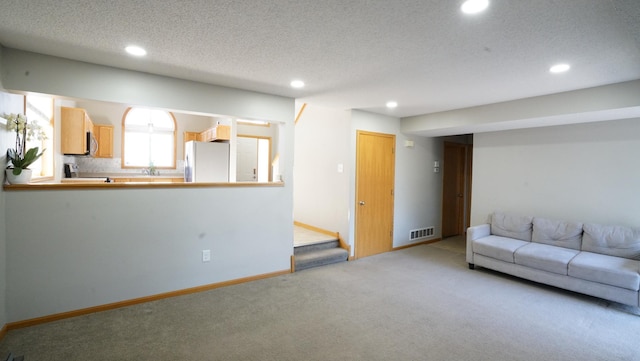unfurnished living room with recessed lighting, visible vents, carpet, baseboards, and a textured ceiling