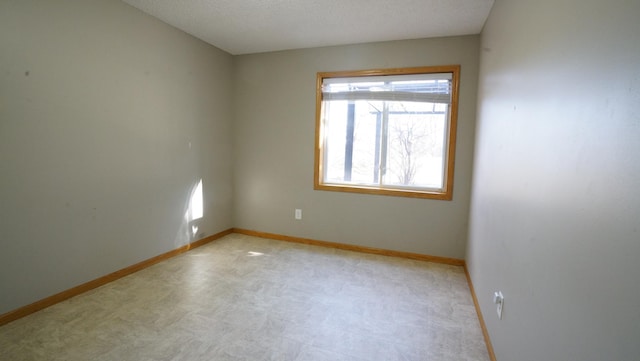 unfurnished room with a textured ceiling, baseboards, and plenty of natural light