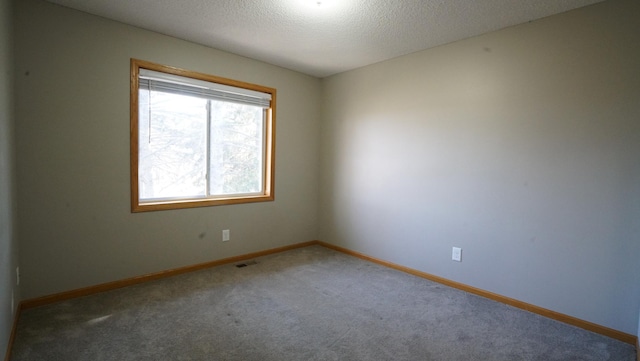 carpeted empty room featuring a textured ceiling, visible vents, and baseboards