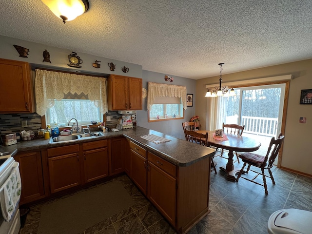 kitchen with a peninsula, a sink, a wealth of natural light, and dark countertops