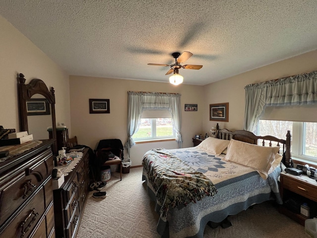 carpeted bedroom featuring a textured ceiling, multiple windows, and a ceiling fan