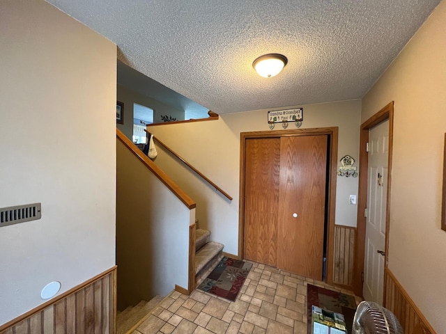 foyer entrance with a textured ceiling and stairway
