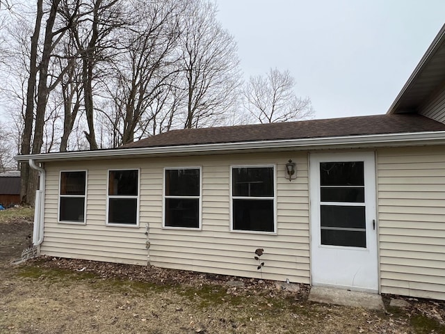 rear view of house featuring roof with shingles