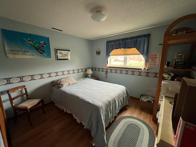 bedroom with a textured ceiling, visible vents, and wood finished floors