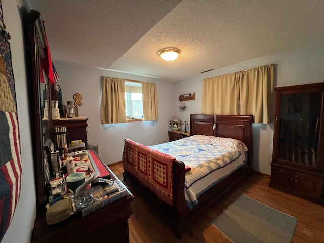 bedroom with wood finished floors and a textured ceiling