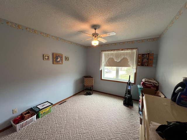 misc room with a textured ceiling, a ceiling fan, carpet, and baseboards