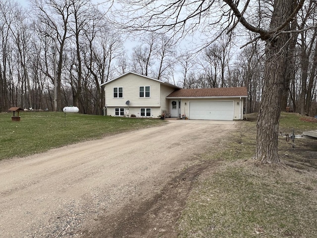tri-level home featuring a garage, dirt driveway, and a front yard