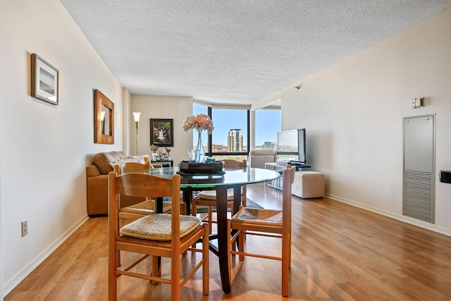 401 1st St Unit 1312, Minneapolis, MN 55401 - dining room with a wall of windows, light wood finished floors, a heating unit, a textured ceiling, and baseboards