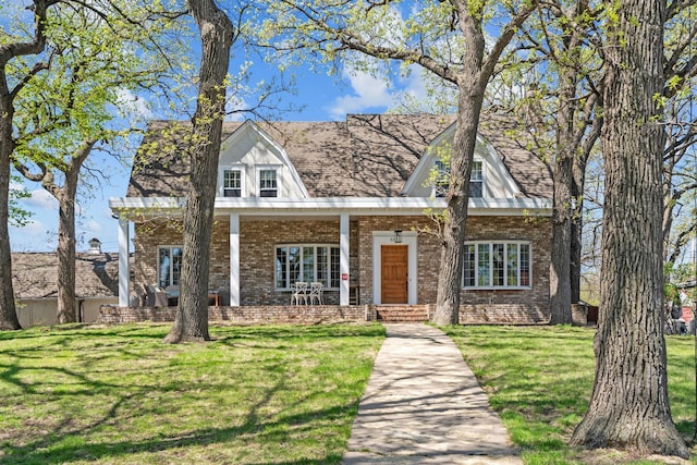 view of front of home featuring brick siding, a front yard, and covered porch