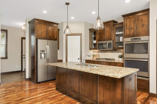 3839 189th Ln NW, Oak Grove, MN 55303 - kitchen featuring stainless steel appliances, a sink, wood finished floors, tasteful backsplash, and glass insert cabinets