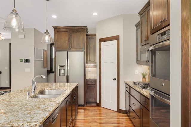 3839 189th Ln NW, Oak Grove, MN 55303 - kitchen featuring a sink, appliances with stainless steel finishes, light wood-style flooring, decorative light fixtures, and light stone counters