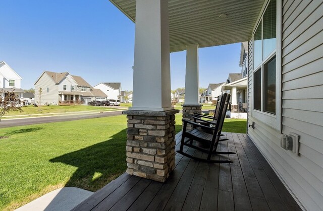 wooden deck featuring covered porch, a residential view, and a yard