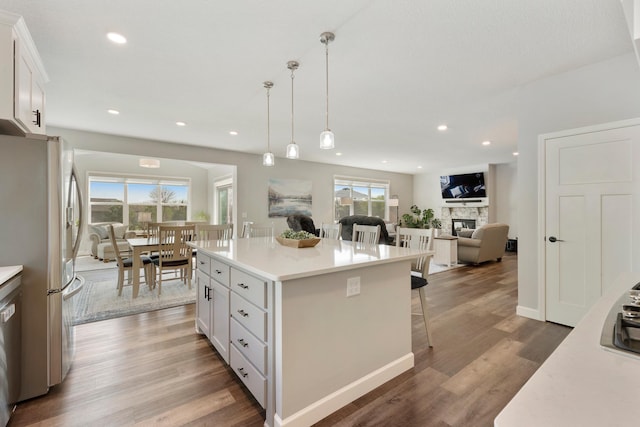 kitchen featuring appliances with stainless steel finishes, a kitchen bar, white cabinets, decorative light fixtures, and light countertops