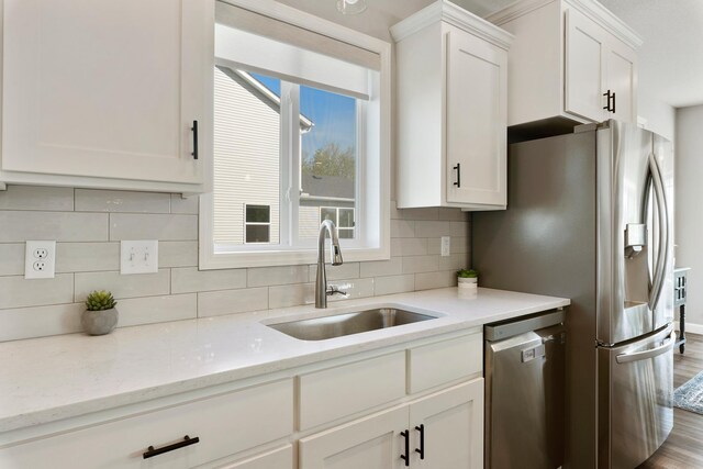 kitchen with dishwasher, a sink, white cabinetry, and backsplash