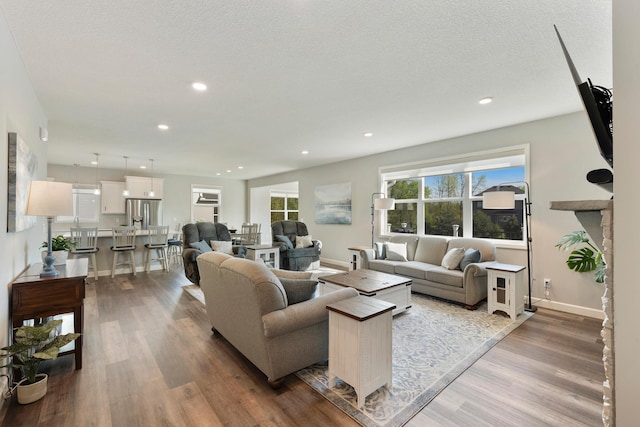 living area with wood finished floors, baseboards, recessed lighting, and a textured ceiling