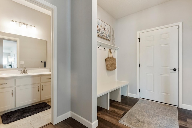 mudroom with a sink, dark wood finished floors, and baseboards