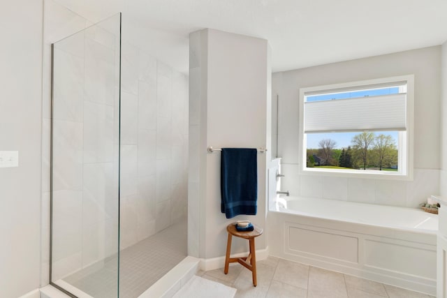 bathroom with a garden tub, tiled shower, tile patterned floors, and baseboards