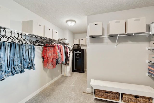 walk in closet with light carpet
