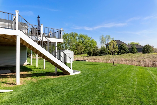 view of green lawn featuring stairs and a deck