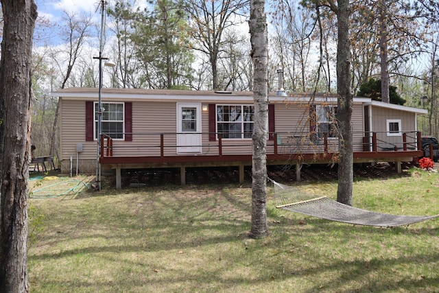 rear view of property featuring a wooden deck and a yard