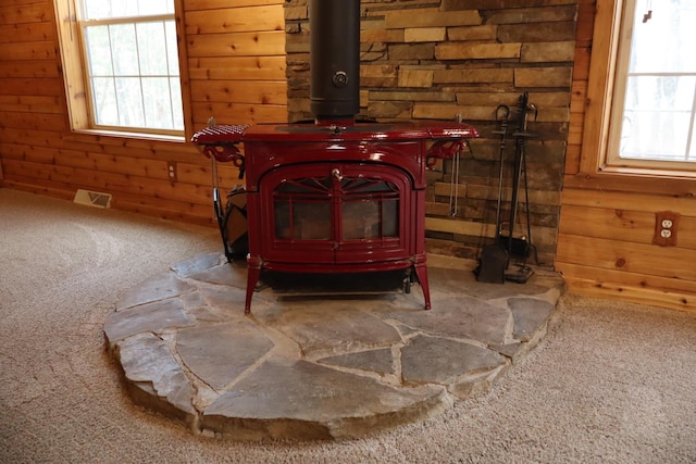 detailed view of a wood stove, carpet floors, and wood walls