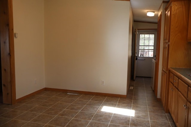 interior space with dark tile patterned flooring and baseboards