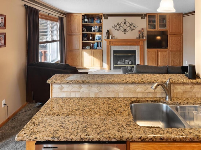 2052 Wilhelm Ct, Shakopee, MN 55379 - kitchen featuring a sink, brown cabinetry, light stone counters, a fireplace, and carpet floors