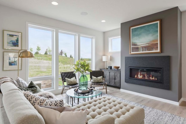 sitting room featuring baseboards, recessed lighting, wood finished floors, and a glass covered fireplace